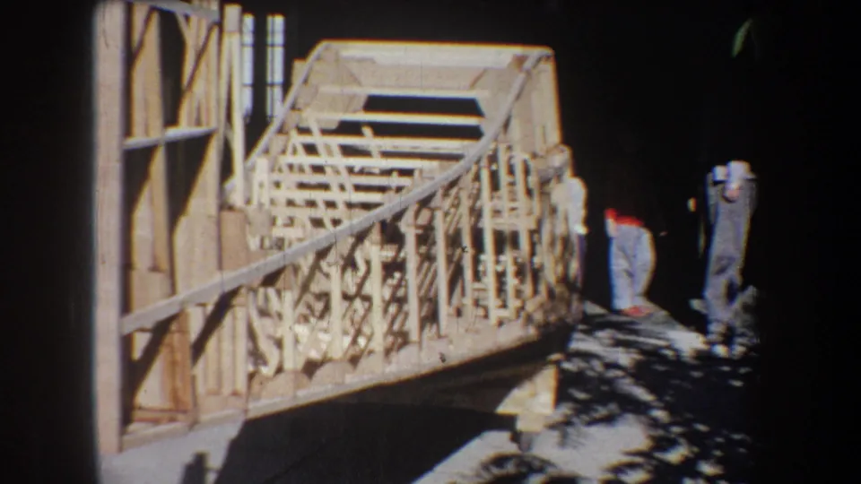 1965 Volmer Yucaipa 8mm frame showing unfinished timber railings with two adult men standing near the work area.