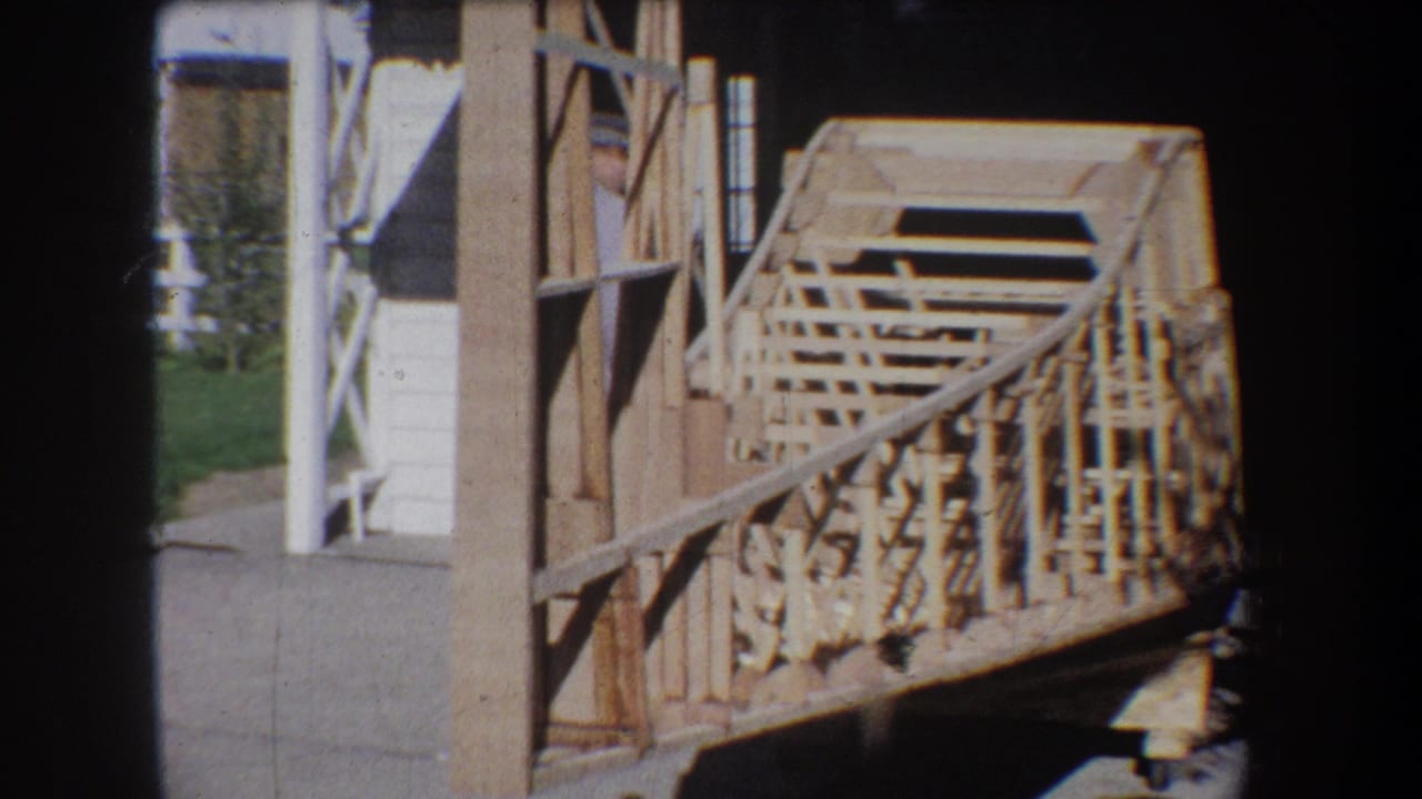 1965 Yucaipa-area 8mm frame showing an unfinished wooden bridge or walkway with rail framing beside a structure.