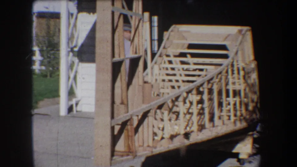 1965 Yucaipa-area 8mm frame showing an unfinished wooden bridge or walkway with rail framing beside a structure.
