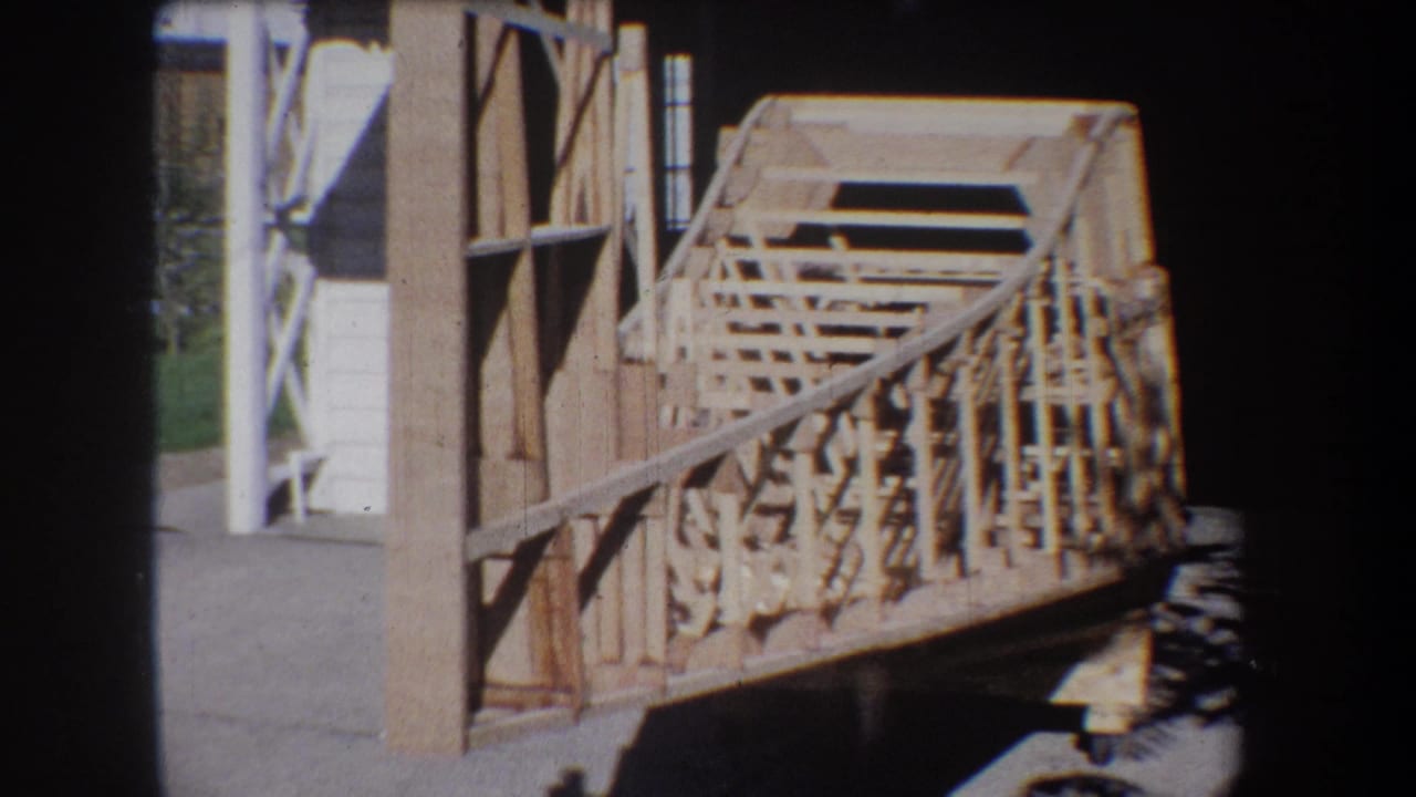 Side view of unfinished wood framing and railings near a structure.