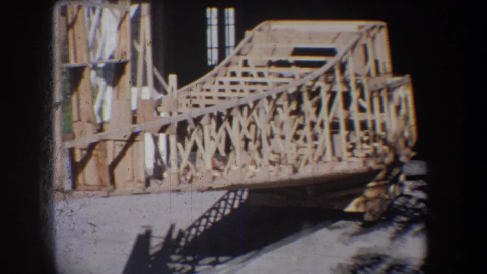 Close 8mm view of unfinished wood rail bracing and deck framing, with strong shadows on the ground in the Yucaipa-area setting.
