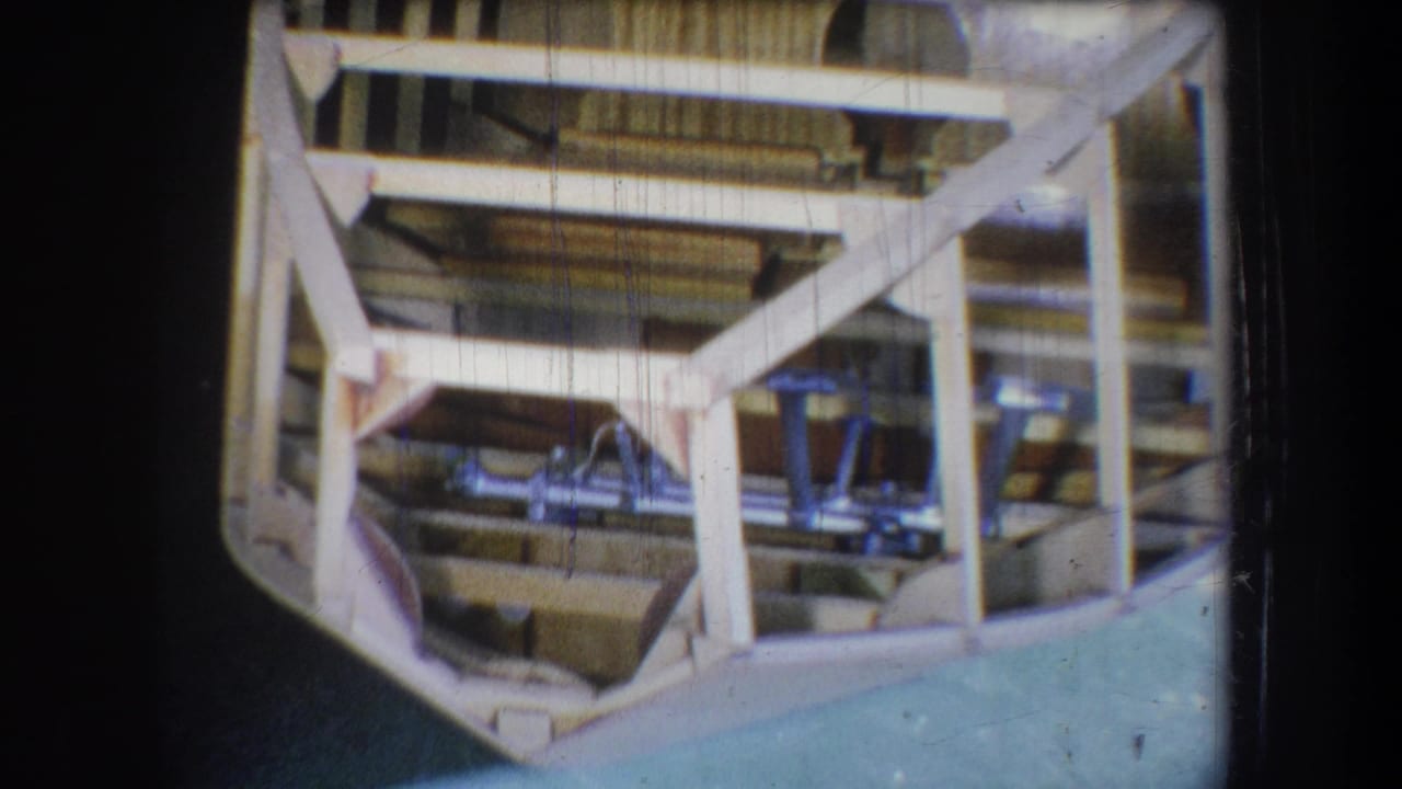 A steady 8mm view of the unfinished wooden boat interior, showing structural beams and blue-painted seating elements.