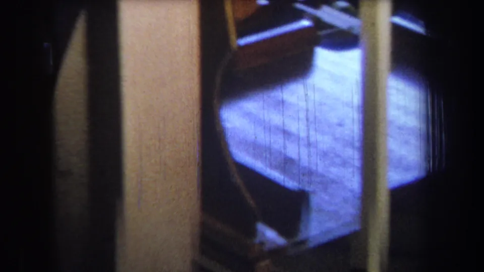 1965 Yucaipa 8mm view past pale yellow framing toward a blue-tinted floor and partially visible metal fixture.