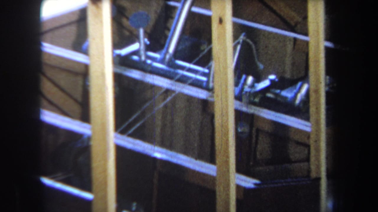 1965 8mm frame from Yucaipa showing an unfinished wooden structure with exposed posts, rails, and metal hardware.