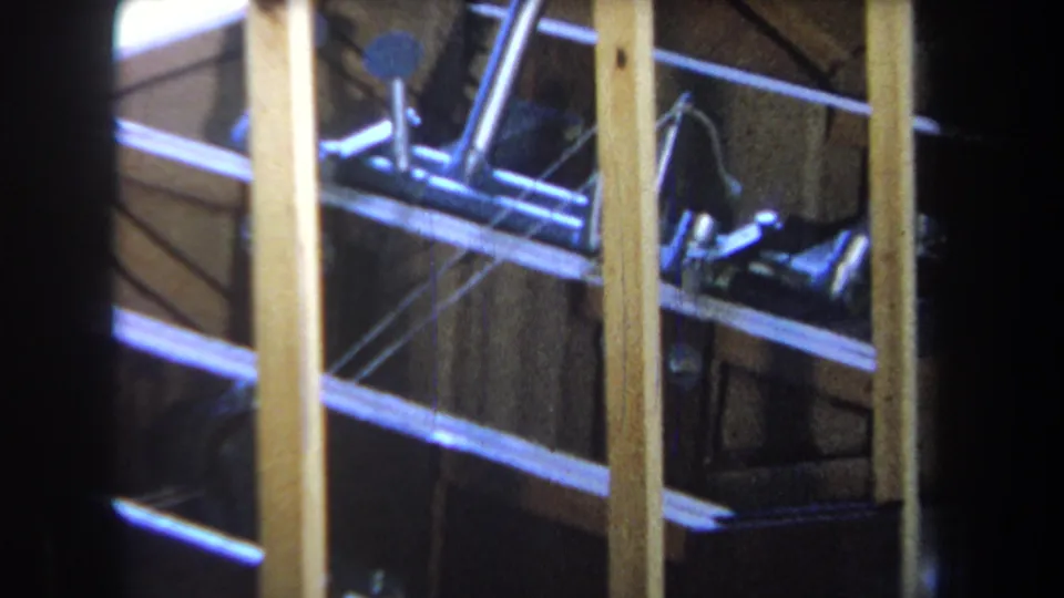 1965 8mm frame from Yucaipa showing an unfinished wooden structure with exposed posts, rails, and metal hardware.