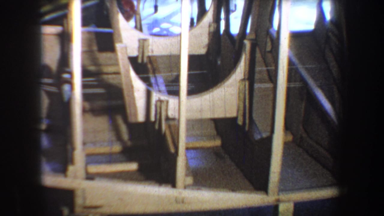 1965 8mm home-movie frame from Yucaipa showing the interior framing of a homemade wooden boat under construction.