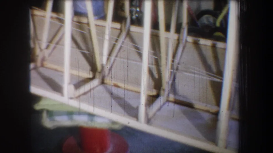 End frame from the 1965 8mm clip showing the homemade boat's side bracing with a partial red stool near the lower edge.