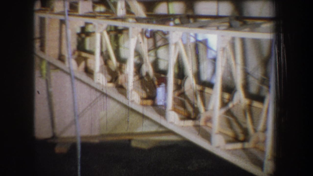 1965 Yucaipa-area 8mm frame showing exposed wood framing, metal braces, cords, and yellow support racks inside construction.