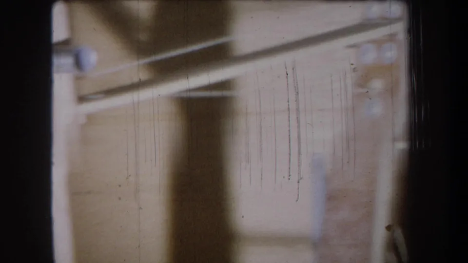 End frame from the 1965 Yucaipa 8mm clip showing blurred timber framing, a dark vertical element and small metal hardware.