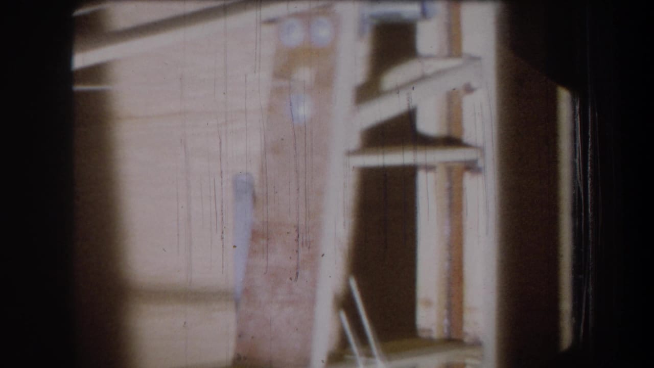 Wooden interior wall and shelf structure seen through scratched film with dark borders.