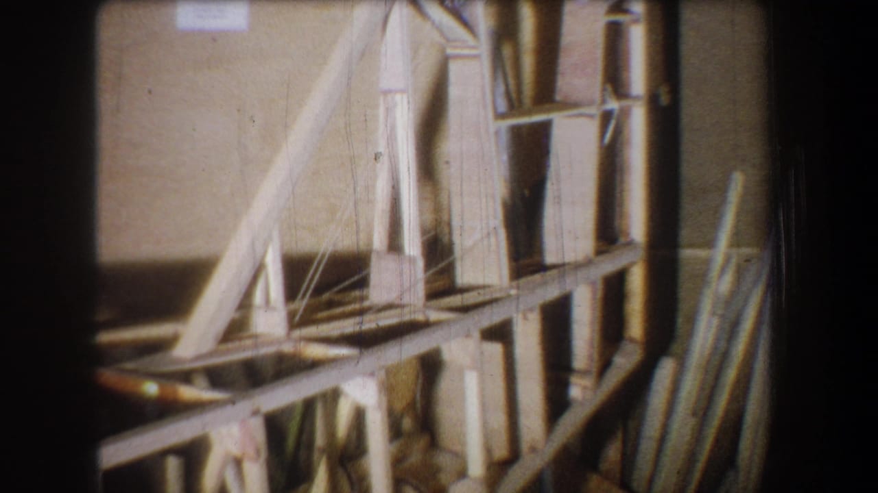 Closer view of wooden framework with boards and shelves along a wall.