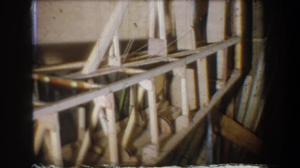 1965 Yucaipa 8mm frame showing stacked boards, shelves, and angled wooden elements in a crowded storage-room corner.