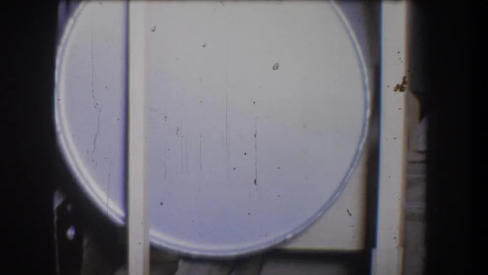 Final 1965 Yucaipa frame showing a pale circular object, possibly a lid or container, beside a vertical bar in the storage area.