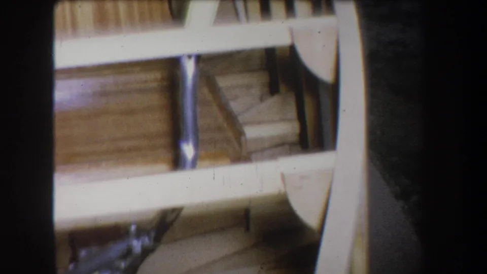 1965 8mm view from Yucaipa showing angled wooden boat framing, light-colored rails, curved ribs, and visible metal supports.