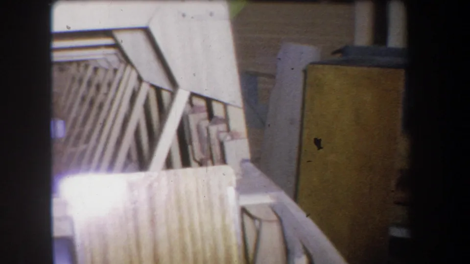 1965 8mm workshop view from Yucaipa with boat ribs, pale planking, curved hull edge, and a cabinet-like storage unit nearby.