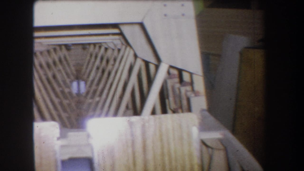 1965 Yucaipa-area 8mm frame showing a wooden scaffold or braced structure inside a dim storage space.