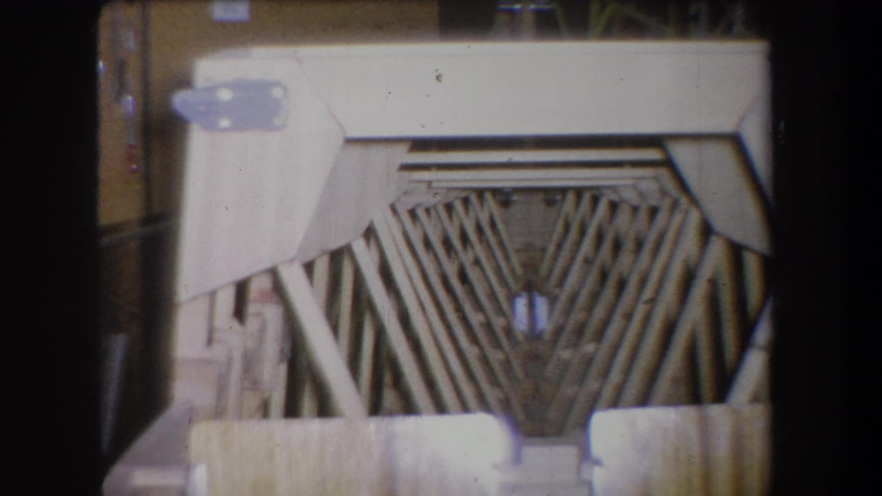 1965 Yucaipa 8mm frame showing a tan wooden structure with angled slats, pale metal brackets and dark film borders.