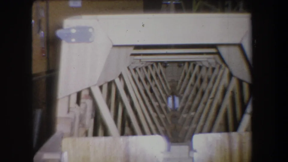1965 Yucaipa 8mm frame showing a tan wooden structure with angled slats, pale metal brackets and dark film borders.
