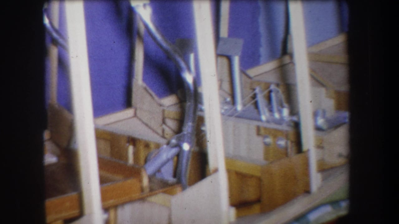 1965 Yucaipa 8mm frame showing a homemade-looking wooden and metal model with white vertical supports and a purple backdrop.