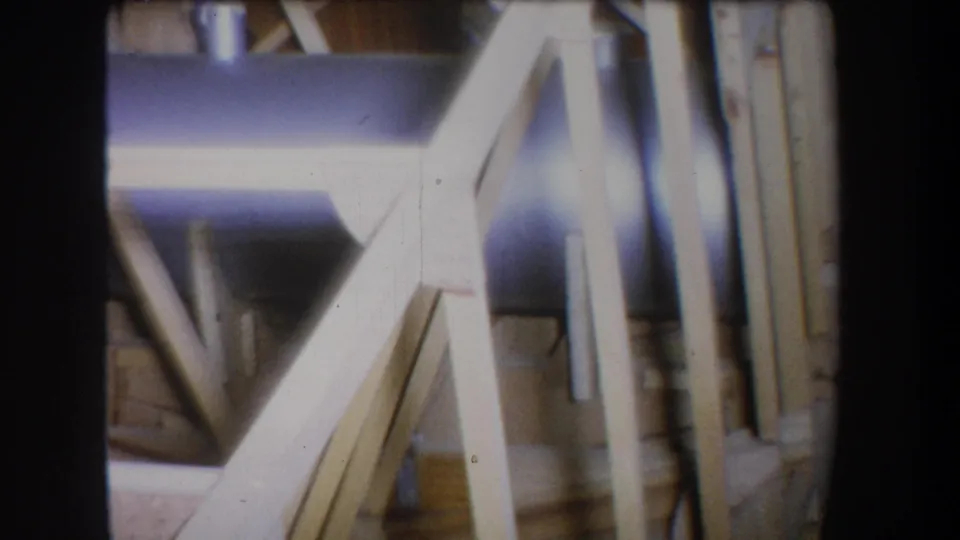 Final 1965 Yucaipa frame holds on unfinished wood supports, diagonal beams, and a bluish metal pipe or tank with visible 8mm grain.