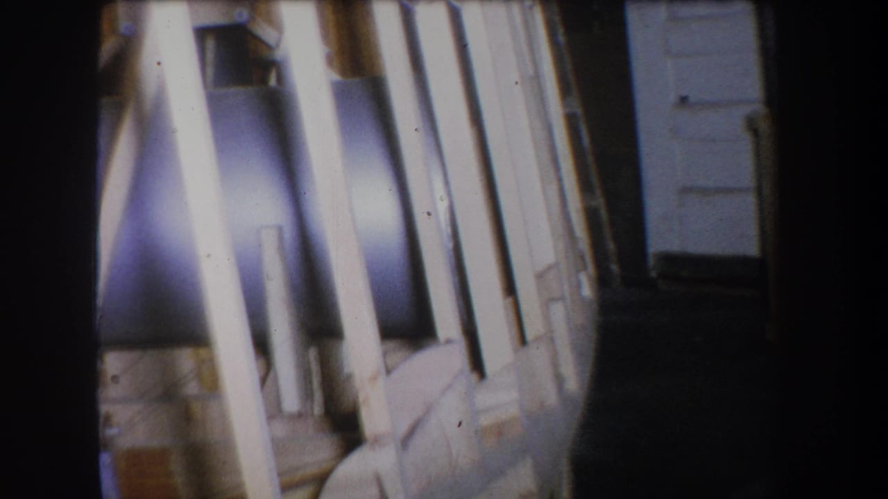 1965 Yucaipa home-movie frame showing a thick dark pipe or tank section partly obscured by pale wooden braces.