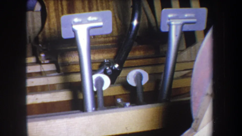 A steady close-up shows the metal pedal rods, flat tops, pivots, and surrounding woodwork in the 1965 8mm clip.