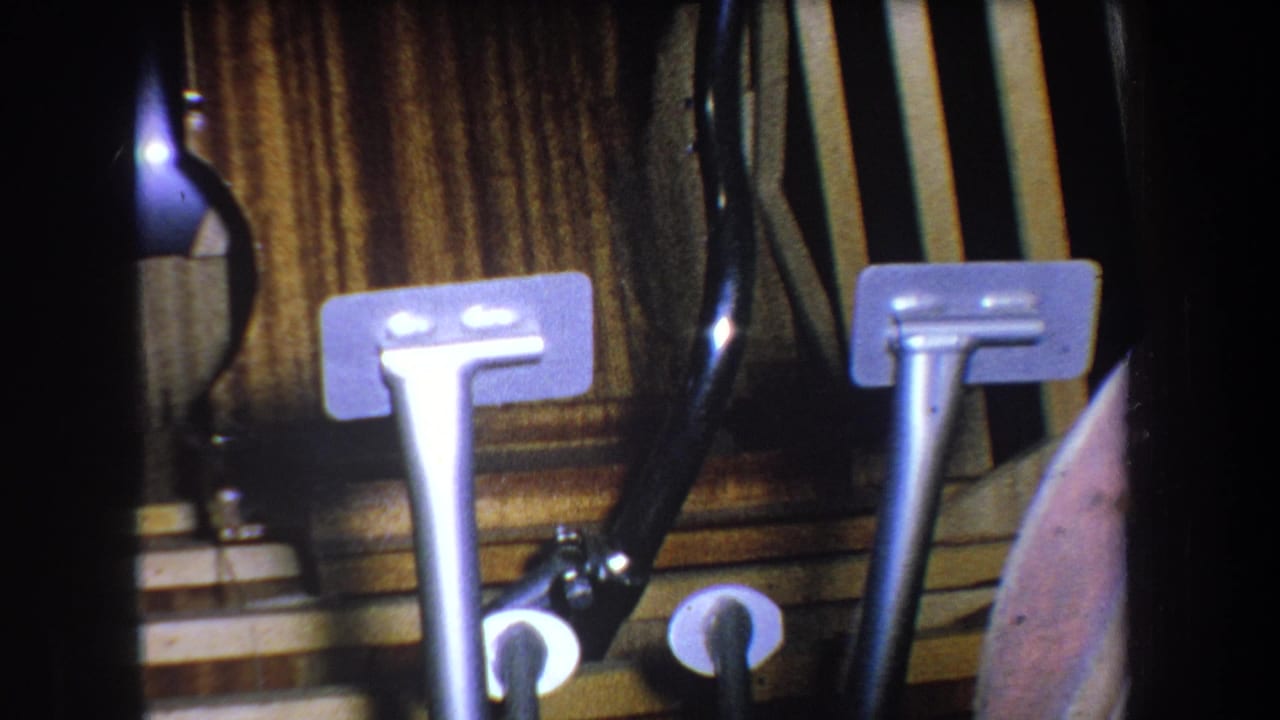 1965 Yucaipa home-movie frame with two upright metal components, black tubing, round wall openings, and wood paneling.