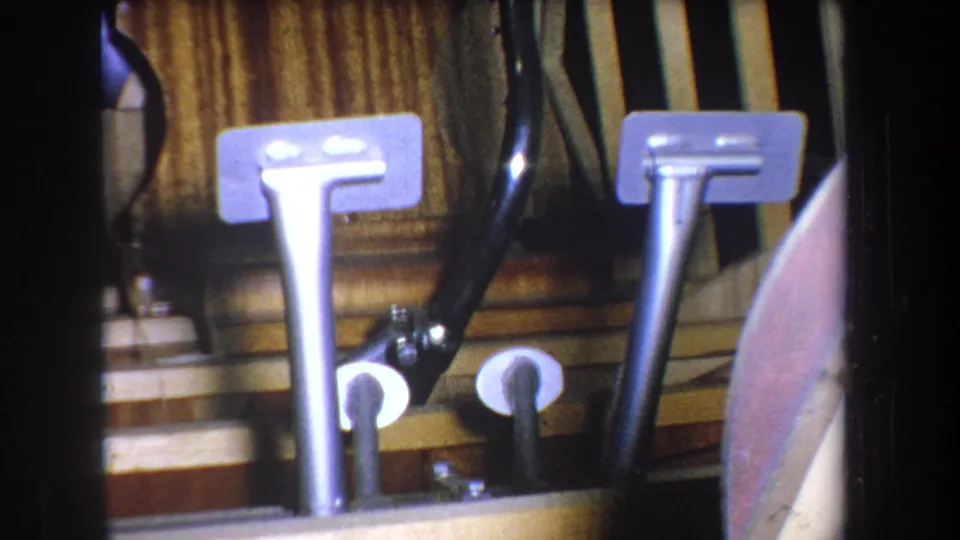 1965 Yucaipa 8mm frame showing basement utility hardware with metal uprights, dark tubing, and wood paneling.