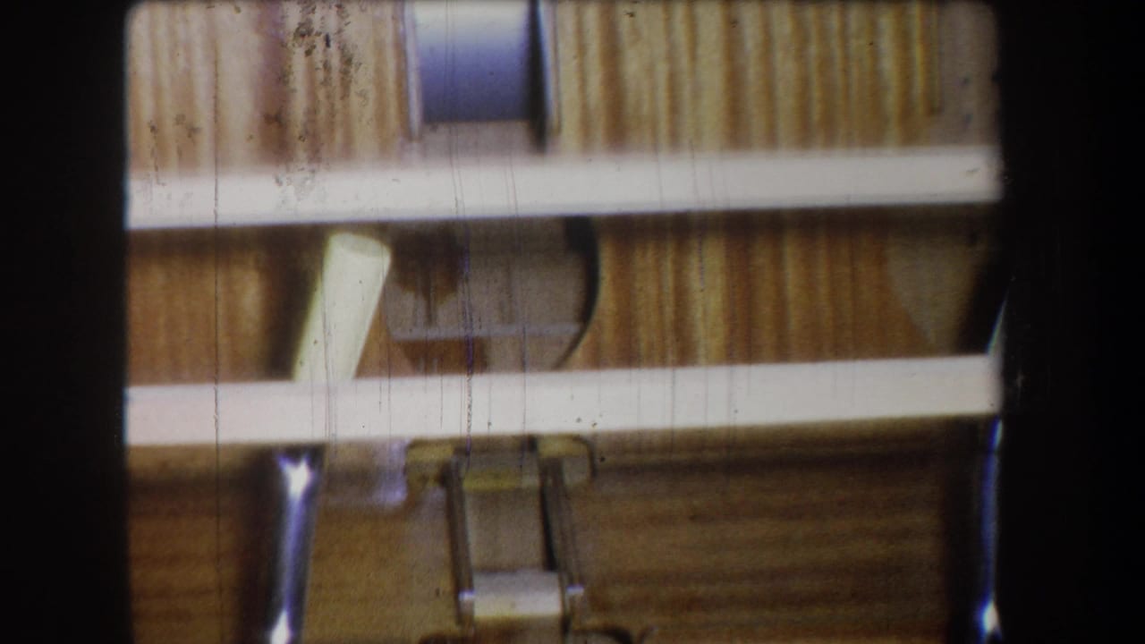 1965 8mm frame from Yucaipa showing close interior construction details with wood boards, rails, hardware, and shadowed supports.