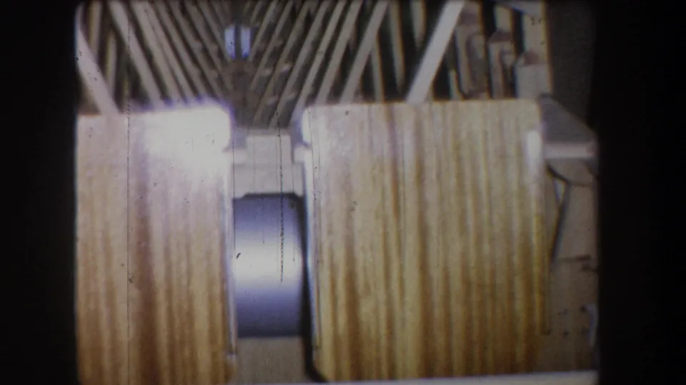 1965 Yucaipa frame showing diagonal interior bracing, vertical boards, a round fixture, and bright exposure flare on 8mm film.
