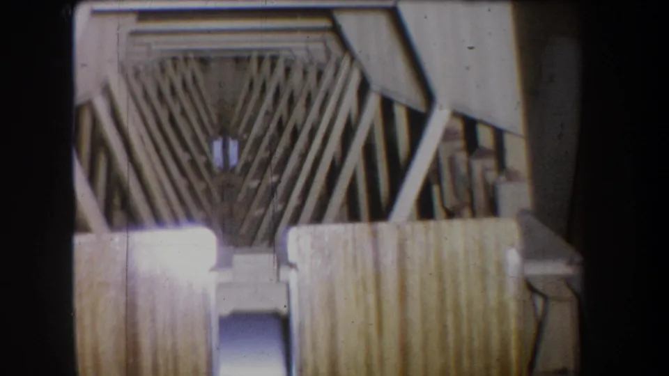 1965 Yucaipa 8mm frame with diagonal trusses, pale framing members, vertical boards, and a dark round fixture inside the structure.