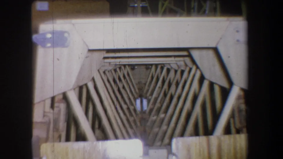 1965 home-movie frame from Yucaipa-area footage showing V-shaped rods, horizontal bars, and pale metal paneling with visible film wear.