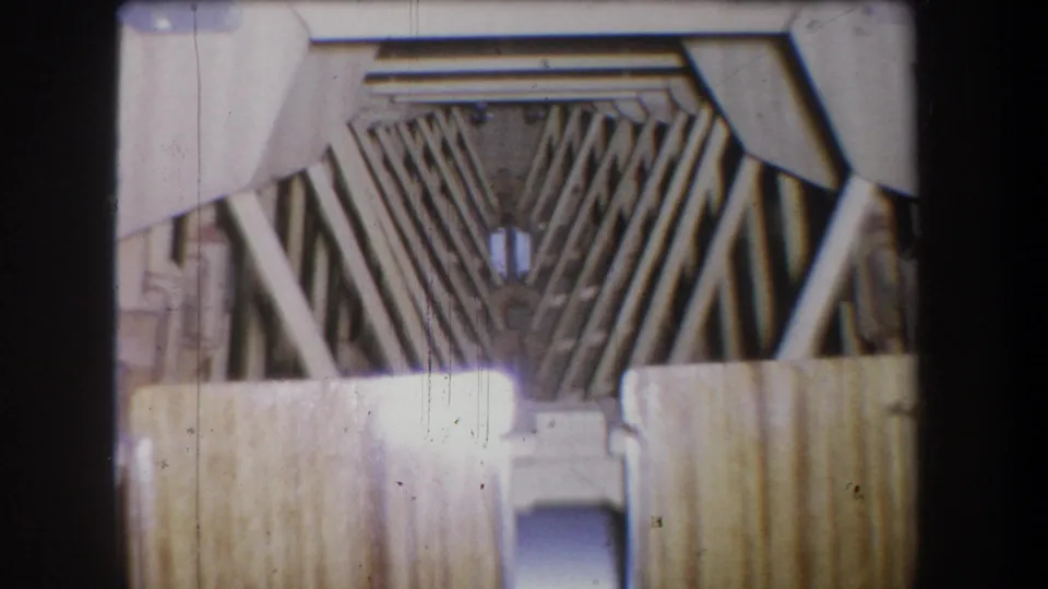 Final 1965 Yucaipa-area 8mm frame showing a pale metal structure, V-shaped rod pattern, horizontal bars, and visible film scratches.