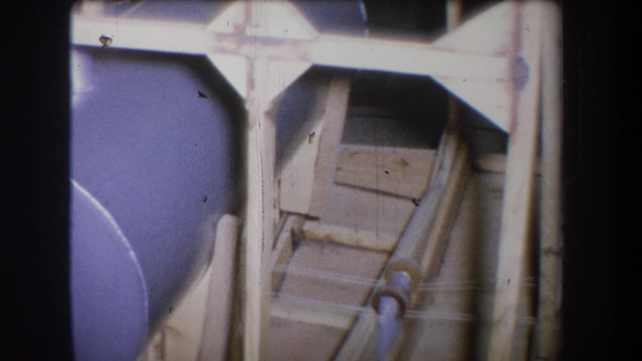 Industrial pipes and framing beside a curved purple tank surface.