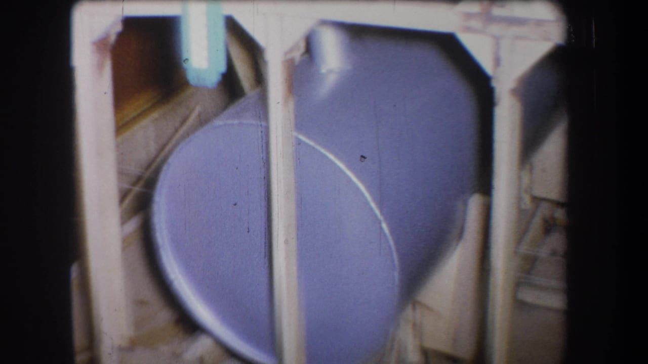 1965 Volmer Yucaipa 8mm frame showing a blue tank behind pale wooden supports and dark film-gate edges.