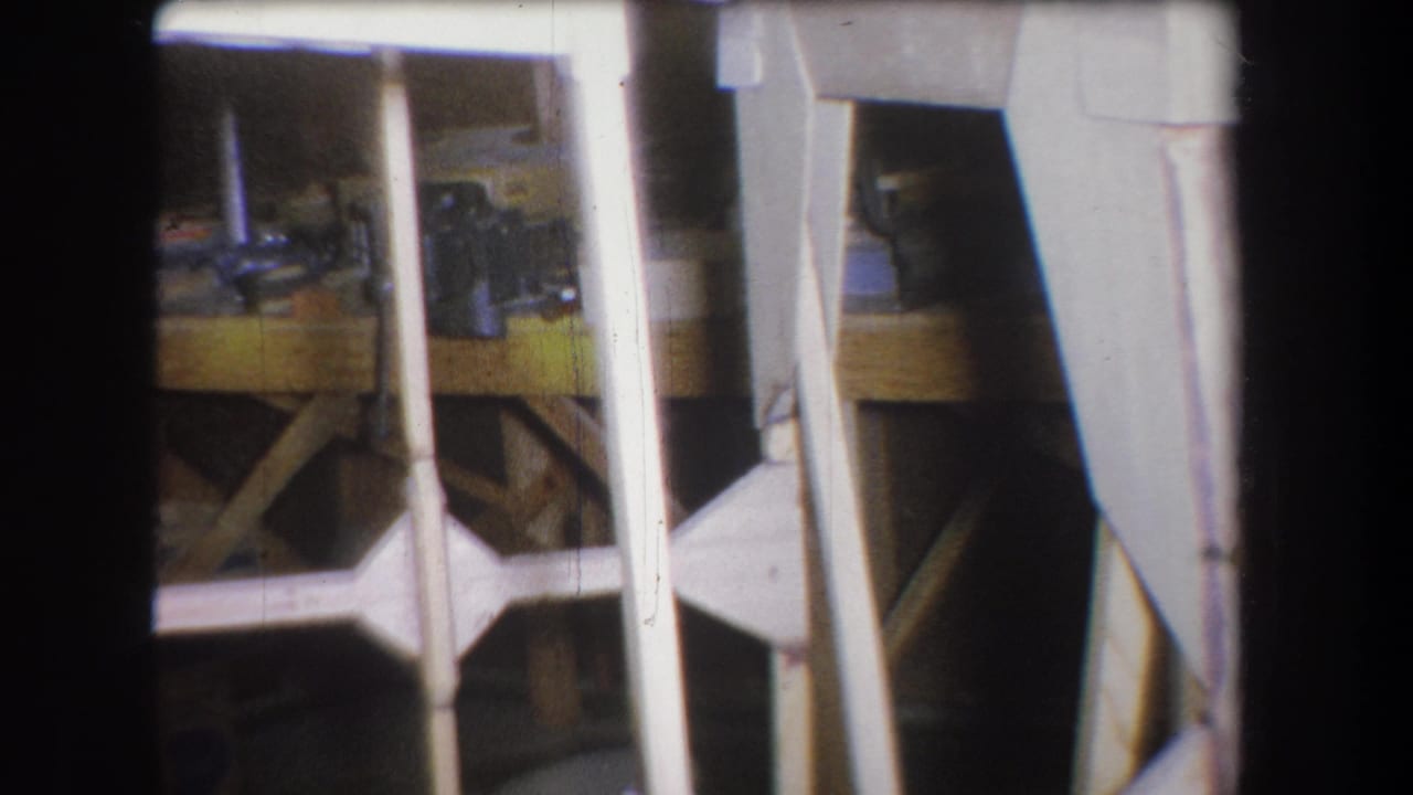 Garage framing with a workbench and small mechanical items behind white rails.