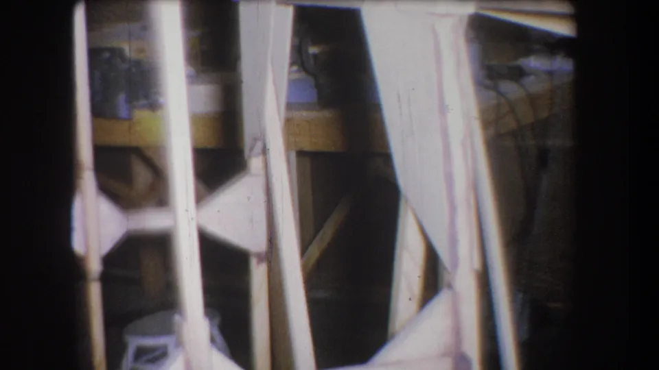 1965 Yucaipa garage frame showing white structural pieces, a workbench, scattered objects, and a small stool or bucket near the bottom.