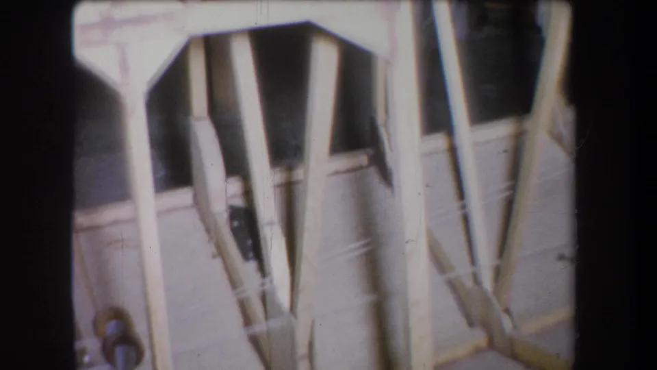 Close 1965 Yucaipa home-movie view of wood framing, angled supports, and metal hardware in a shadowed space.