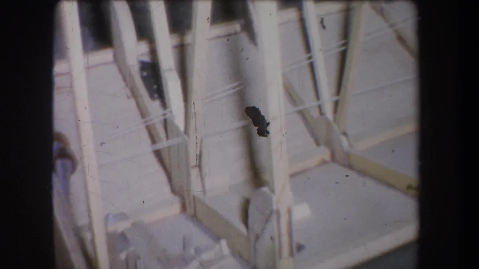 Tilted 8mm view of tan wood framing in the Yucaipa storage area, with scratches and a dark emulsion mark visible.