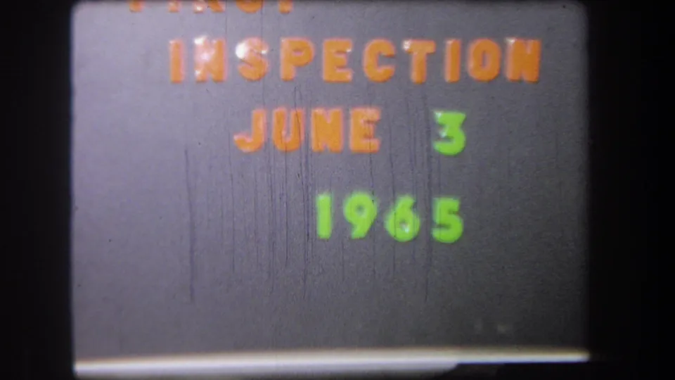 Second frame of the 1965 inspection title card, with the same orange and green date lettering within black film borders.