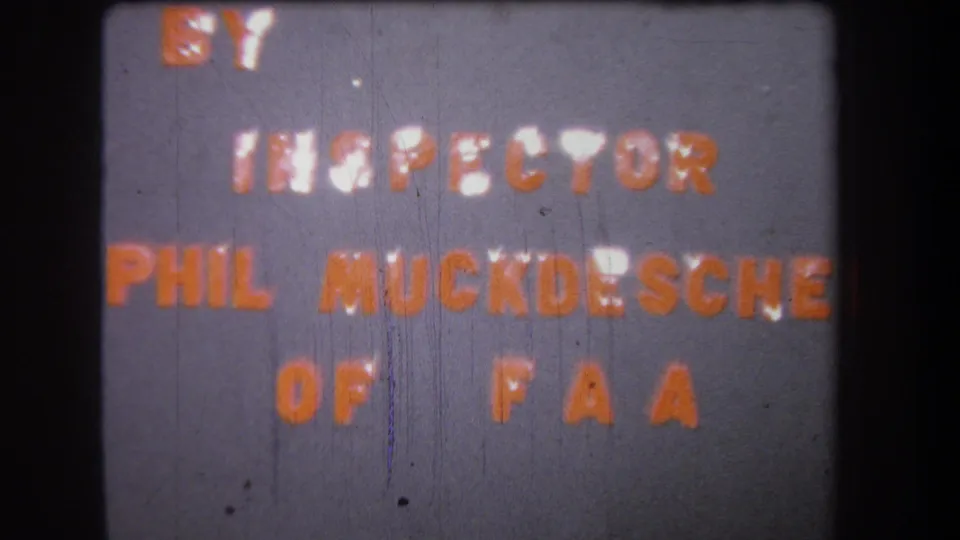 1965 home-movie title card with orange lettering crediting Inspector Phil Muckdesch of FAA, shown with grain and vertical wear.
