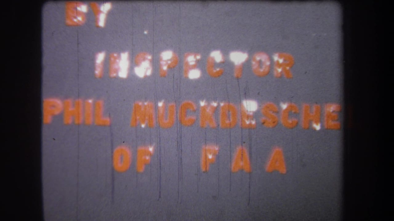 1965 8mm frame showing a gray title card with orange text reading partly as BY INSPECTOR PHIL MUCKDESCH OF FAA.