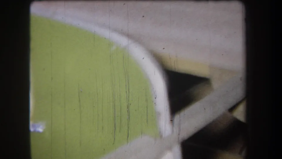 1965 8mm close-up of an unidentified green and white industrial or aviation-related object with soft focus and film scratches.