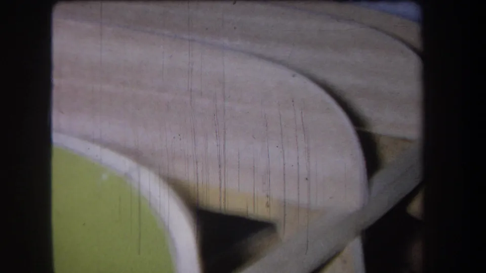 1965 8mm close-up showing an unidentified pale and green object surface, possibly part of an inspection subject, with visible archival film texture.