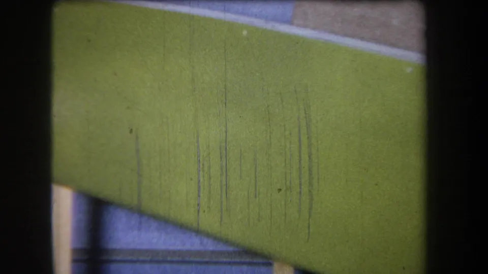 End frame from the 1965 Yucaipa-area 8mm clip, showing a green curved band, partial beige surface, blue-gray lower area, and scratched film texture.