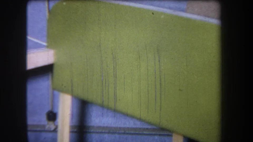 1965 8mm frame from Yucaipa showing a green painted wooden tray or stacked wooden object with pale supports and visible film wear.