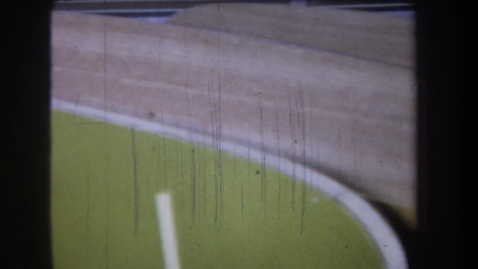 1965 8mm close-up of stacked wooden tray rims in Yucaipa, showing curved pale wood, green painted surfaces, grain, and scratches.
