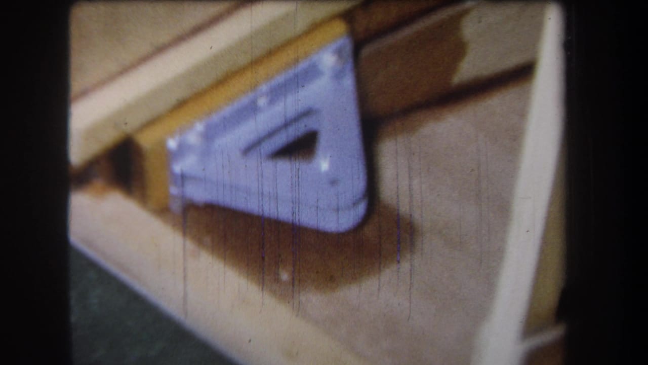 Angled close-up of the same wood surface and purple metal bracket.