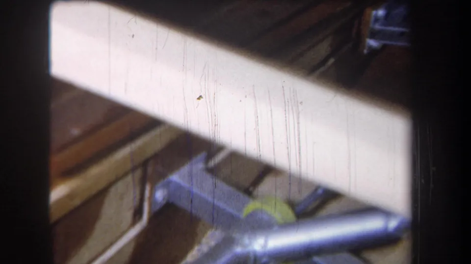 A 1965 Volmer Yucaipa attic view with a galvanized duct, wood framing, and a bright pale surface partly obscuring the scene.