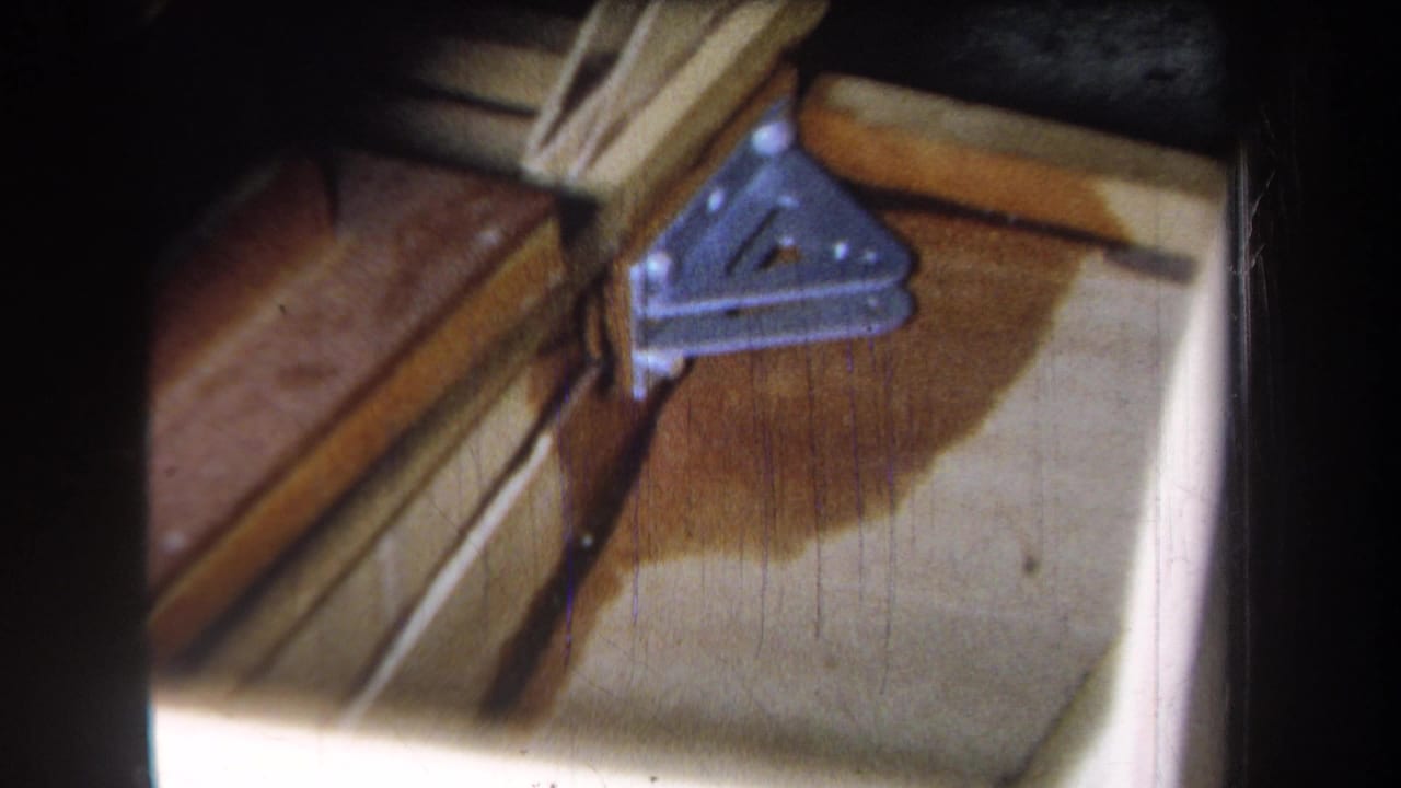 Metal support bracket and wood beams seen close up with staining below.